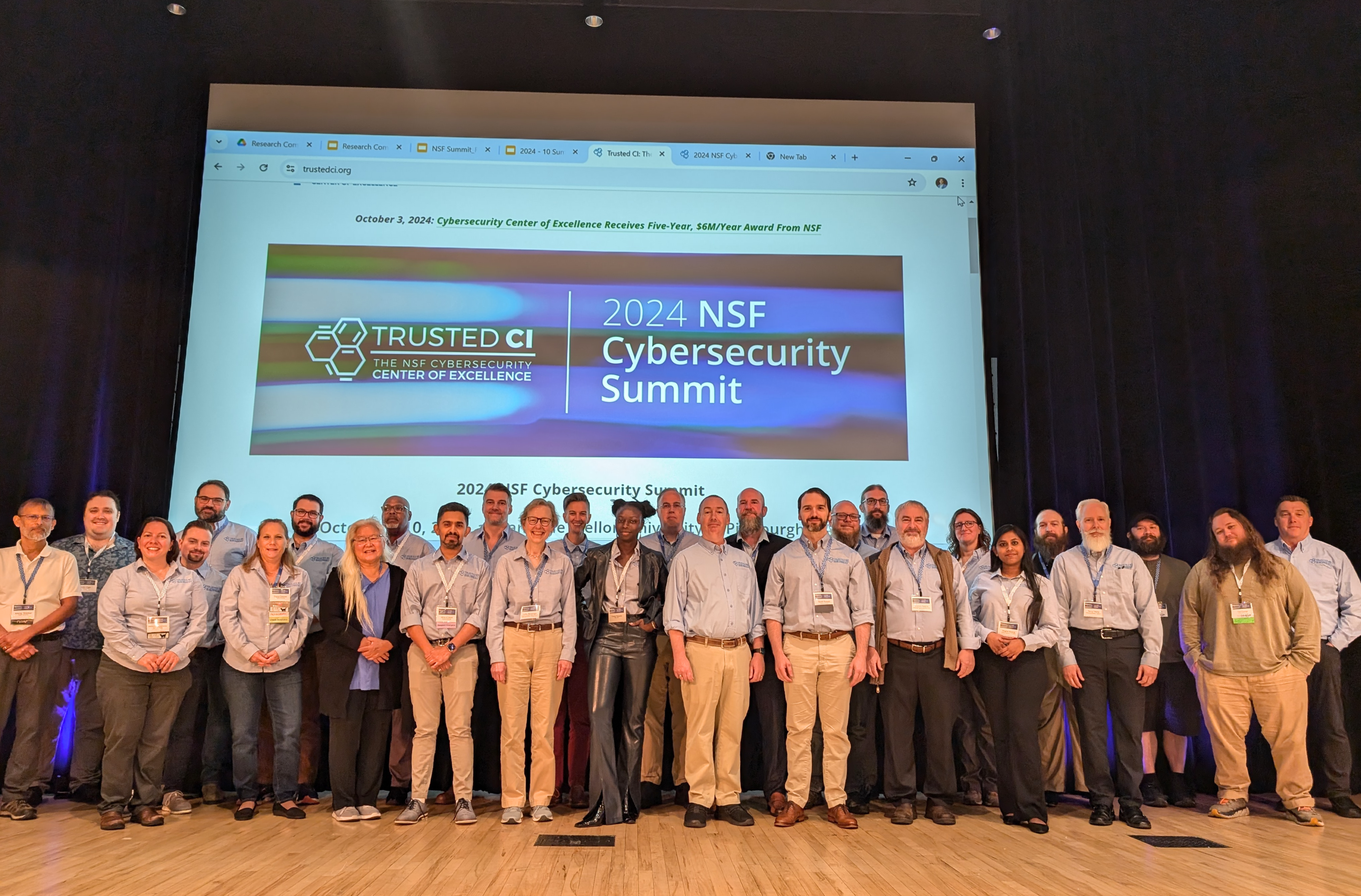 A group of people stand on a stage for a group picture at the Summit. 